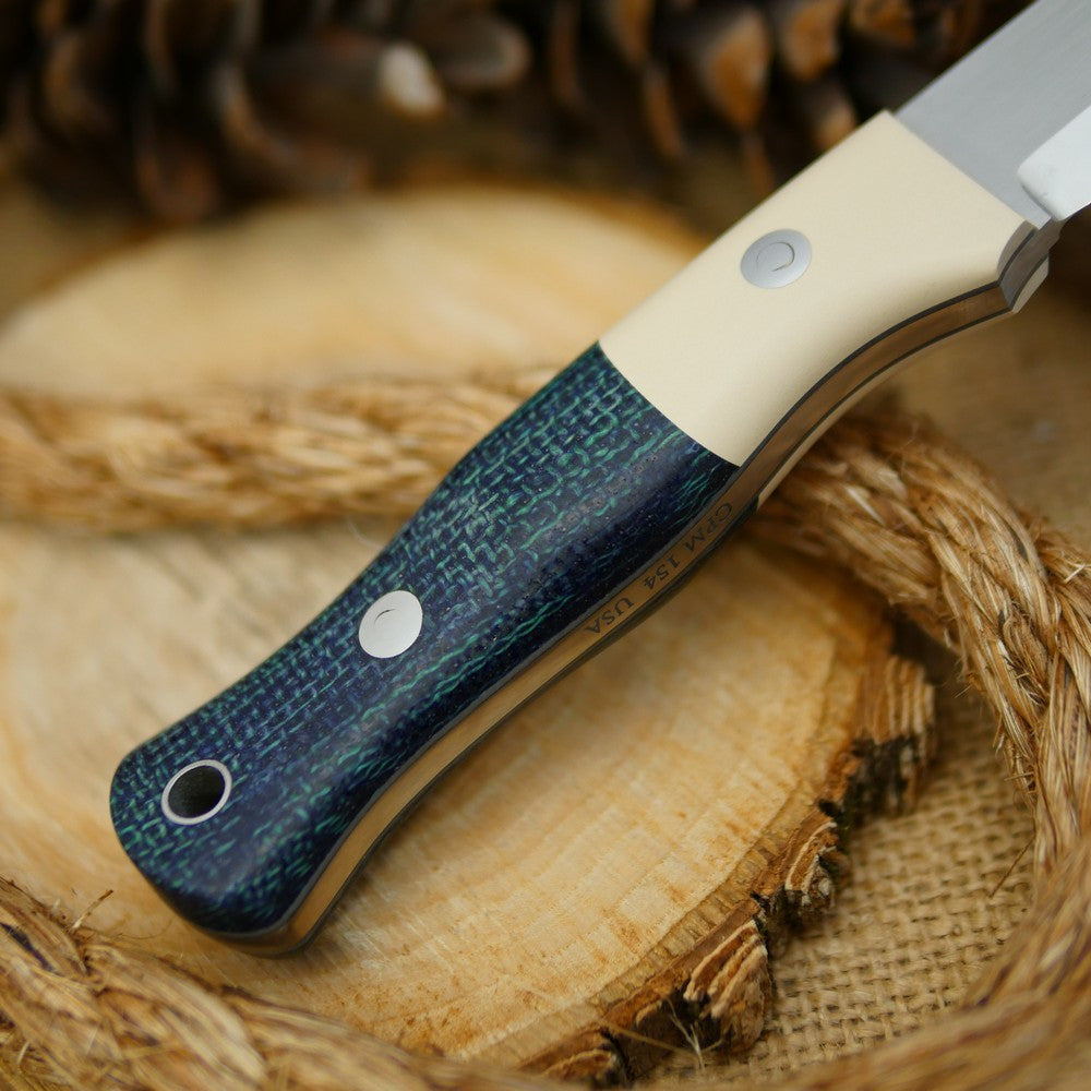 An Adventure Sworn Mountaineer bushcraft knife with navy blue burlap and ivory paper.
