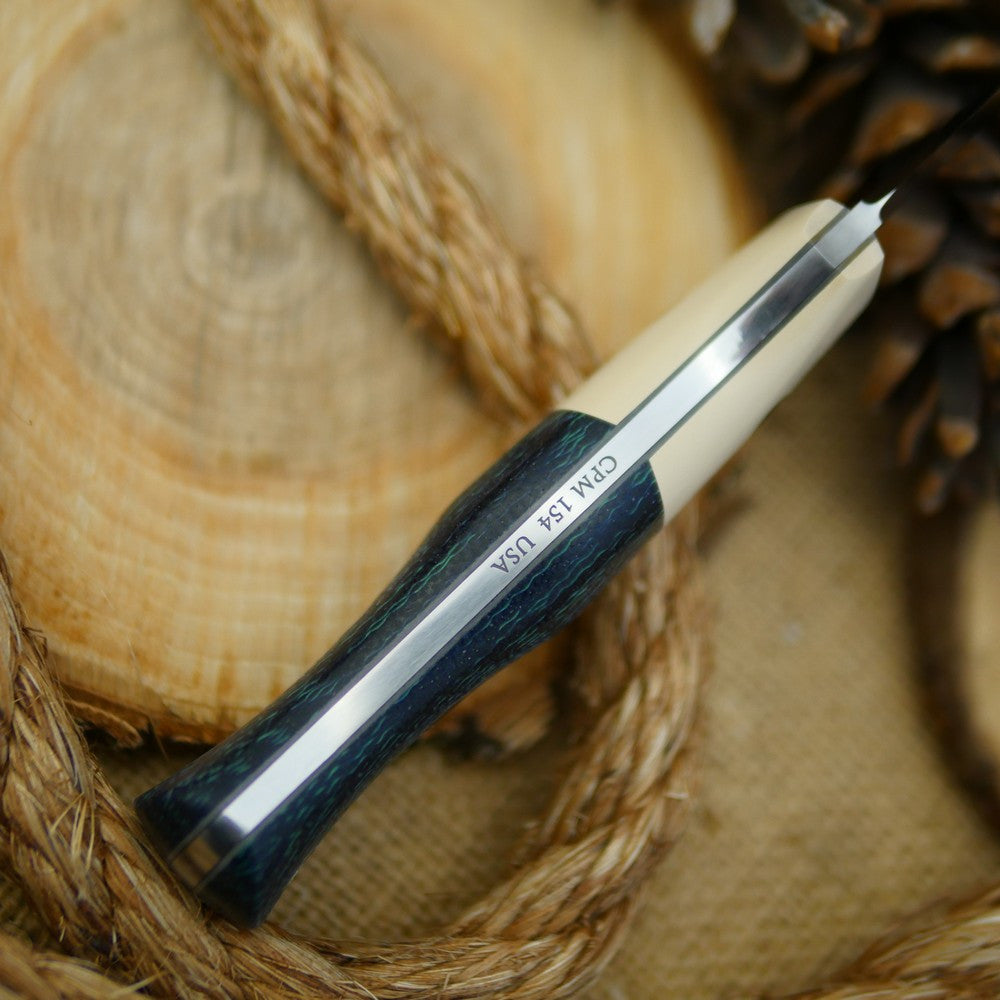 An Adventure Sworn Mountaineer bushcraft knife with navy blue burlap and ivory paper.
