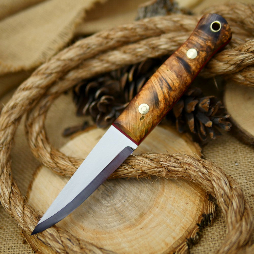 An Adventure Sworn Woodcrafter Bushcraft Knife with dyed box elder handle scales and 1/8 thick red liners