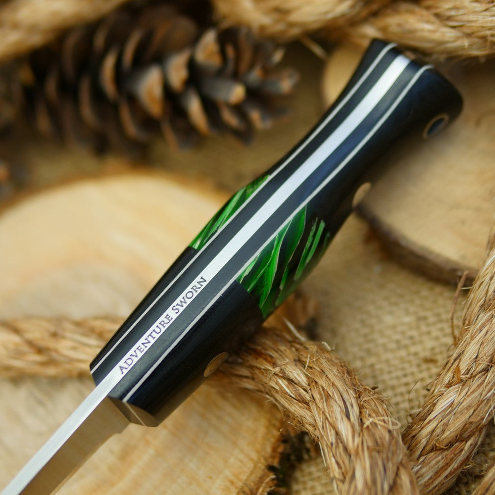 An Adventure Sworn bushcraft knife with black canvas micarta handle scales and green raffir stripes spacer.