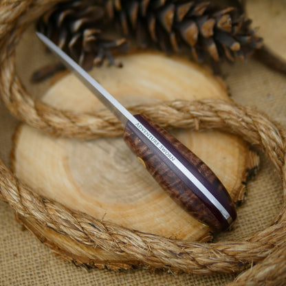 An Adventure Sworn Walker Bushcraft Knife with dark brown curly maple handle scales and thick maroon liners.
