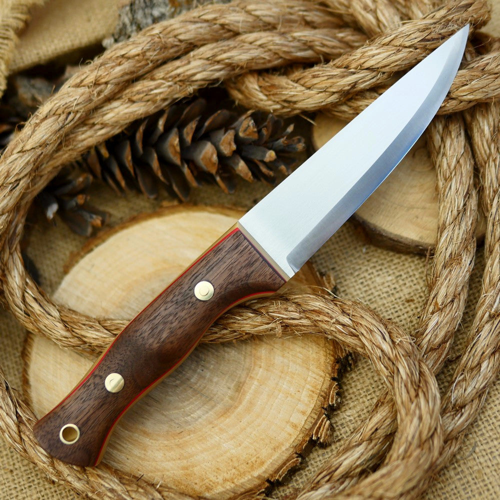 An Adventure Sworn bushcraft knife with walnut handle scales and thick bone linen micarta and thin red liners.