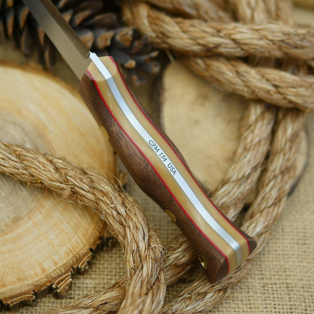 An Adventure Sworn bushcraft knife with walnut handle scales and thick bone linen micarta and thin red liners.