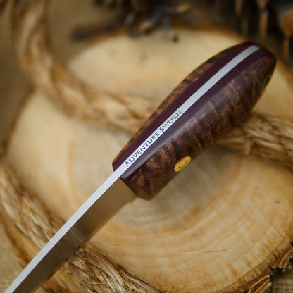 An Adventure Sworn Walker Bushcraft Knife with dark brown curly maple handle scales and thick maroon liners.