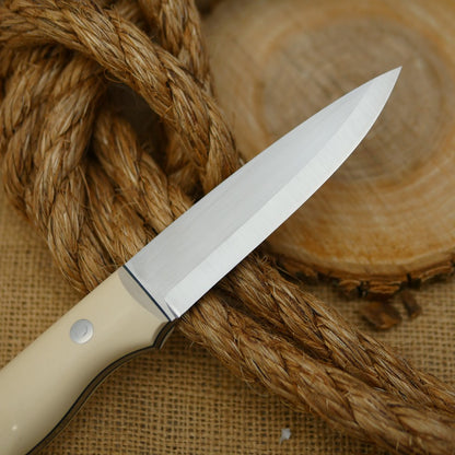 An Adventure Sworn Mountaineer bushcraft knife with ivory paper micarta handle scales and forest green g10 liners.