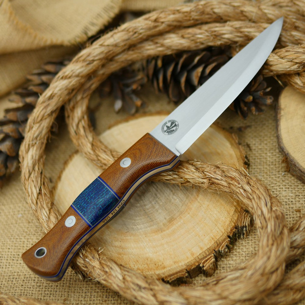 An Adventure Sworn bushcraft knife with natural brown canvas micarta handle scales and navy blue burlap spacer.